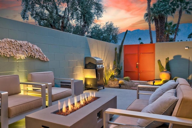 patio terrace at dusk with a grill and an outdoor living space with a fire pit