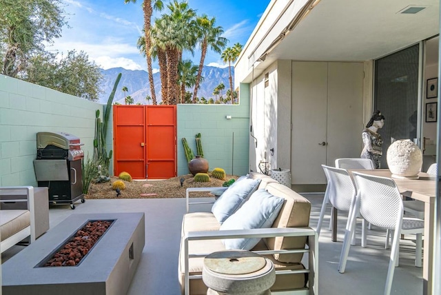 view of patio / terrace featuring grilling area, a mountain view, and an outdoor living space with a fire pit