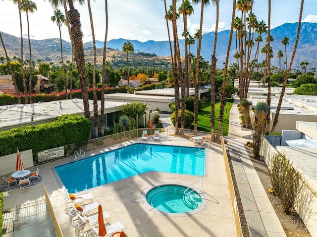 view of swimming pool with a mountain view, a community hot tub, and a patio area