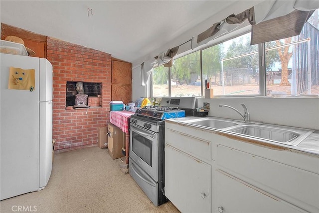 kitchen with gas stove, white cabinetry, sink, white refrigerator, and lofted ceiling