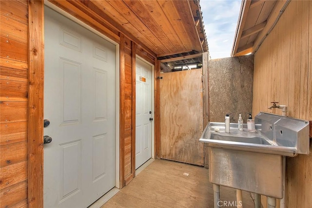 clothes washing area featuring wooden walls and sink