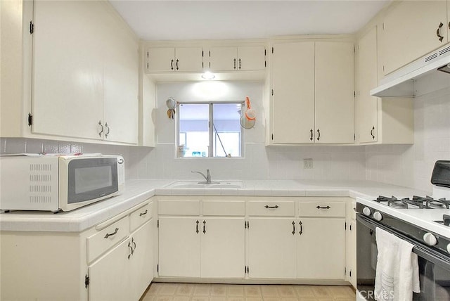 kitchen featuring backsplash, white appliances, sink, and tile countertops