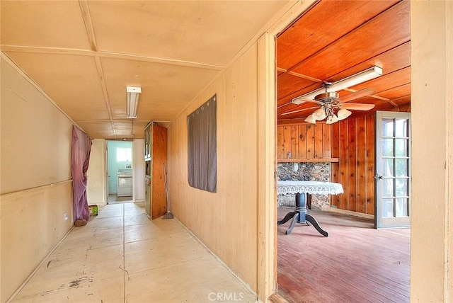 corridor with washer / clothes dryer, wood walls, and light hardwood / wood-style floors