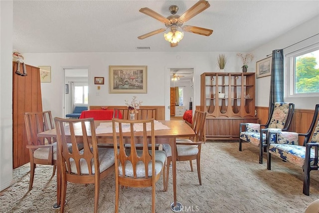 dining space featuring light carpet and wood walls