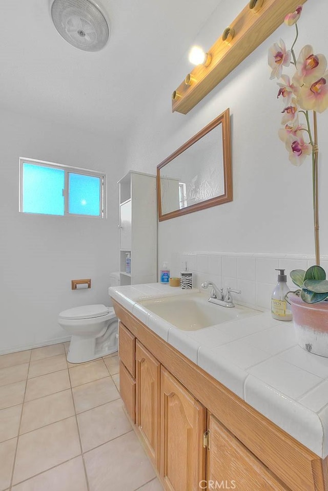 bathroom with toilet, vanity, and tile patterned floors