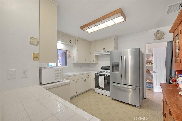 kitchen featuring white gas range oven and stainless steel refrigerator with ice dispenser