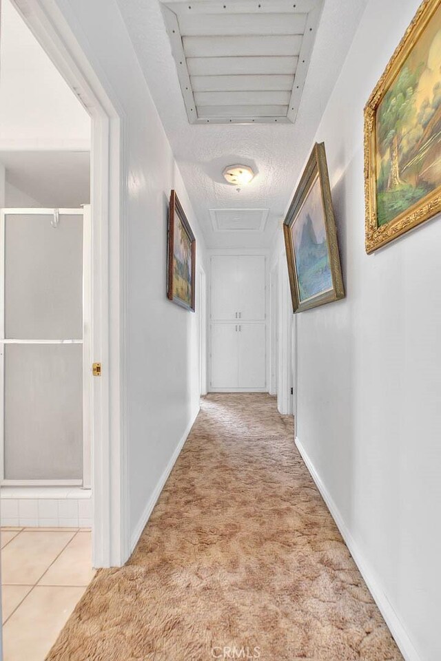 hallway featuring light colored carpet and a textured ceiling