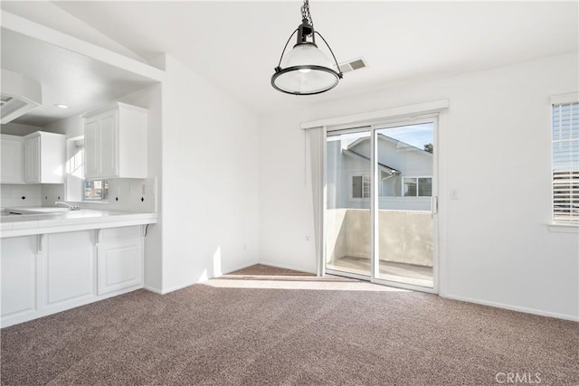 unfurnished dining area featuring light colored carpet and a healthy amount of sunlight