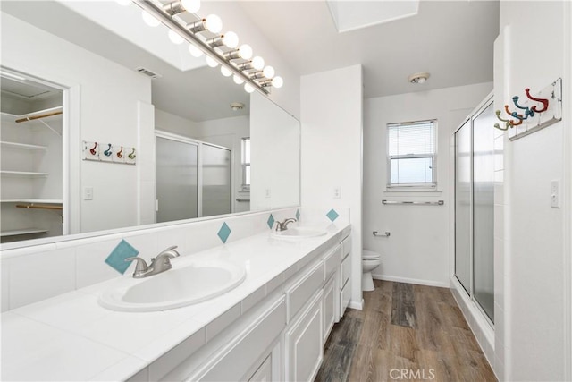 bathroom with hardwood / wood-style floors, vanity, toilet, and an enclosed shower