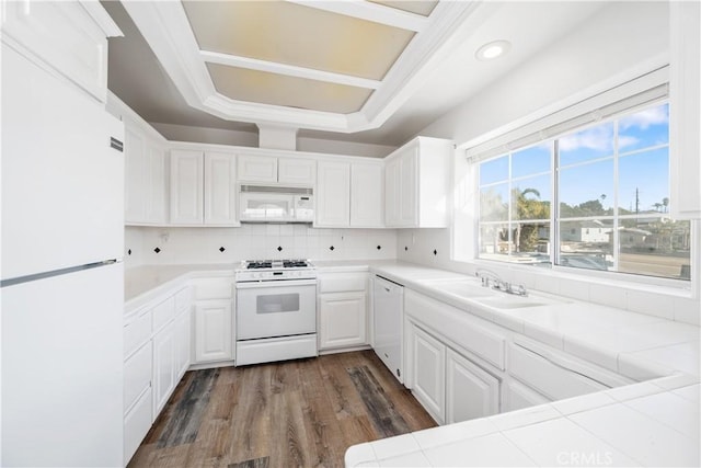 kitchen featuring white appliances, dark wood-type flooring, white cabinets, sink, and tile counters