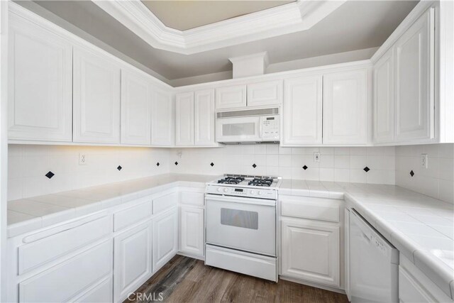 kitchen featuring backsplash, tile countertops, white cabinetry, and white appliances