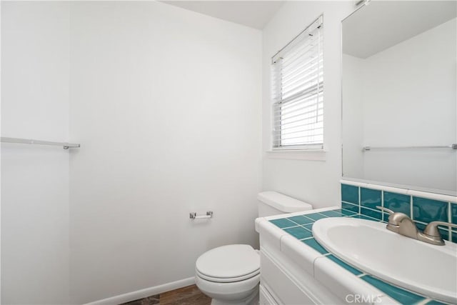 bathroom featuring hardwood / wood-style flooring, vanity, toilet, and tasteful backsplash