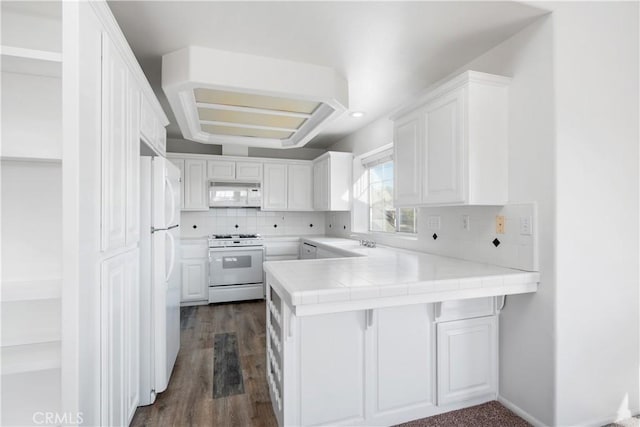 kitchen featuring white cabinets, tile counters, white appliances, and kitchen peninsula