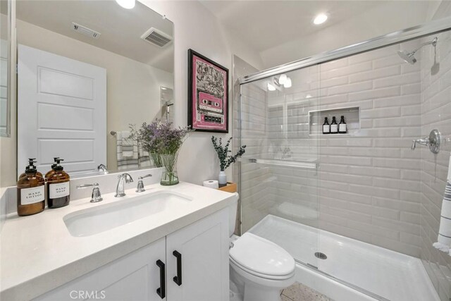 bathroom with a shower with door, toilet, and vanity