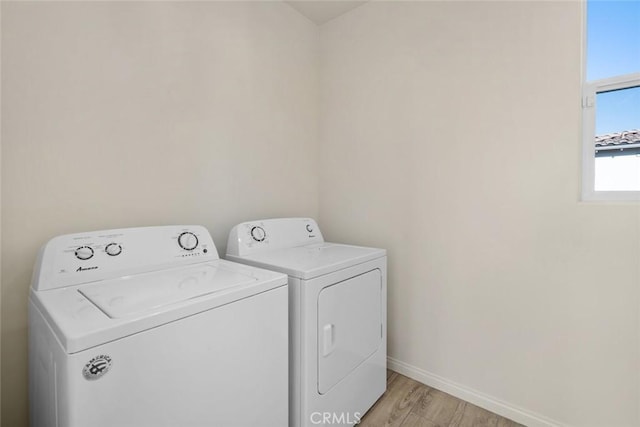 clothes washing area with separate washer and dryer and light hardwood / wood-style flooring