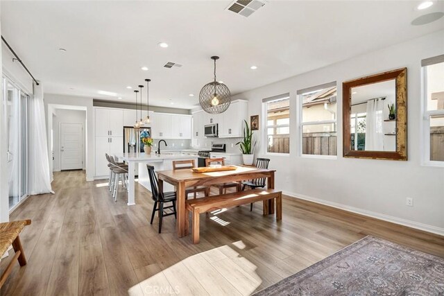 dining area featuring plenty of natural light, sink, and light hardwood / wood-style flooring