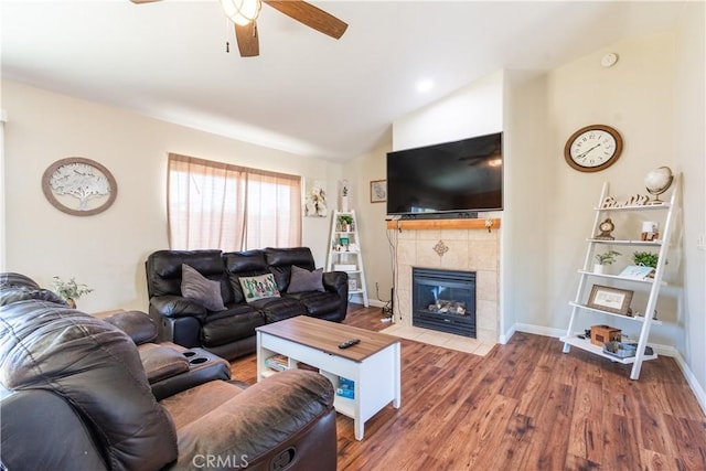 living room with a tiled fireplace, ceiling fan, wood-type flooring, and lofted ceiling