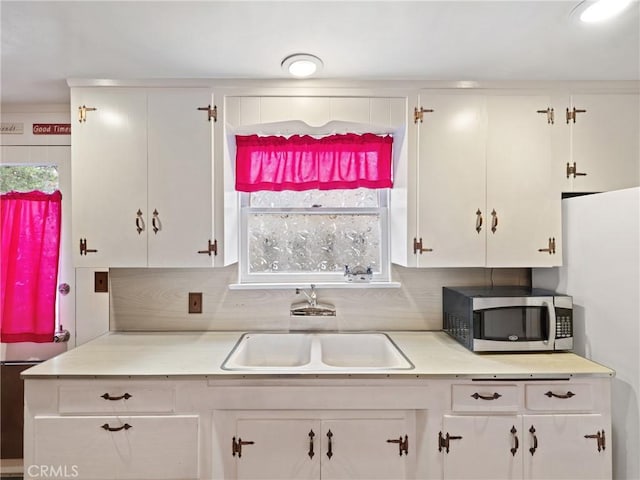 kitchen with decorative backsplash, sink, and white cabinets