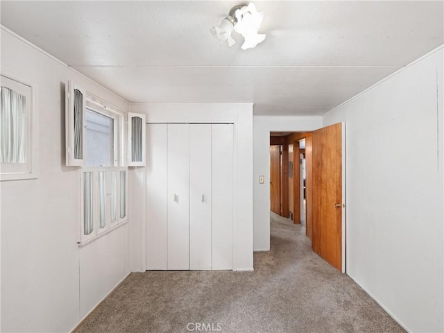 unfurnished bedroom featuring light colored carpet and a closet