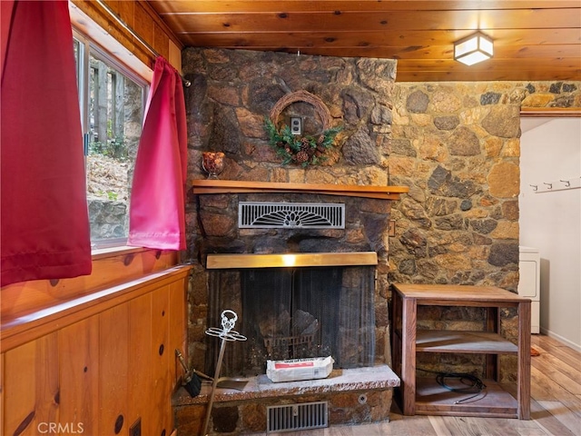 interior details featuring a fireplace, hardwood / wood-style floors, wood walls, and wood ceiling