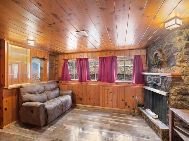 living room with a stone fireplace, wooden walls, hardwood / wood-style floors, and wood ceiling