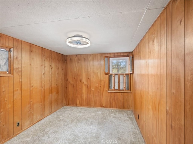 carpeted spare room featuring wood walls