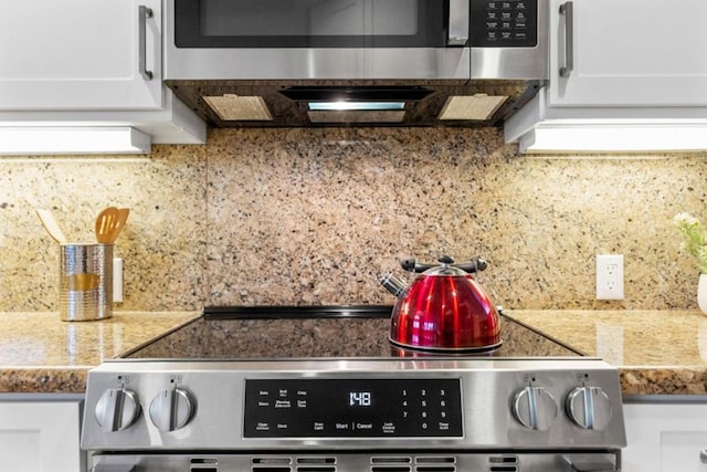 interior space with backsplash, stainless steel appliances, and white cabinetry