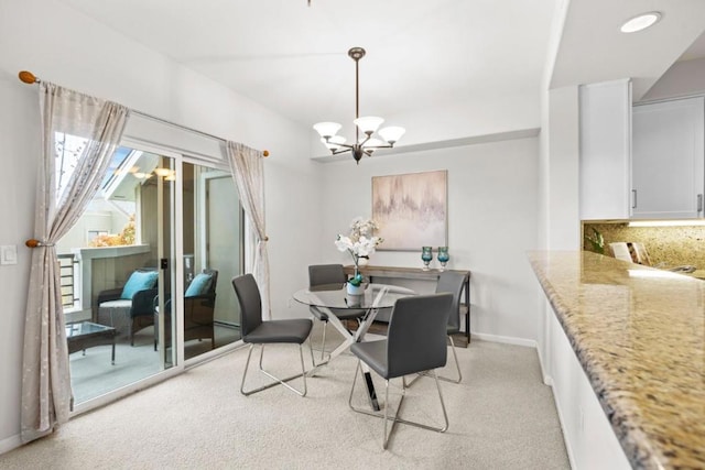 dining space featuring light carpet and an inviting chandelier