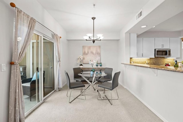 dining room featuring a notable chandelier and light carpet