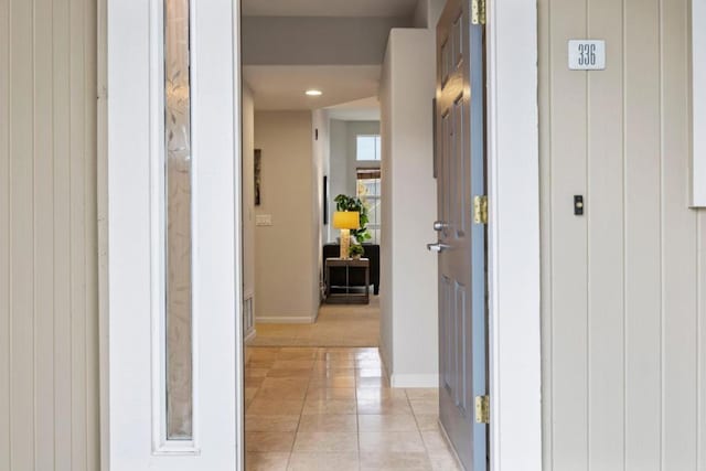 hall featuring light tile patterned flooring and wooden walls