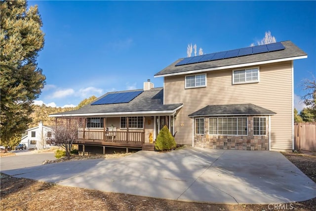 back of house featuring covered porch and solar panels