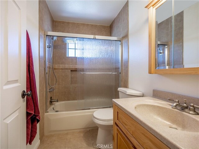 full bathroom featuring vanity, tile patterned flooring, shower / bath combination with glass door, and toilet