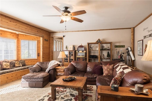 carpeted living room with ornamental molding, ceiling fan, and wood walls