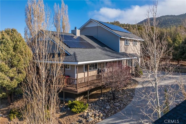 back of house with a deck with mountain view and solar panels