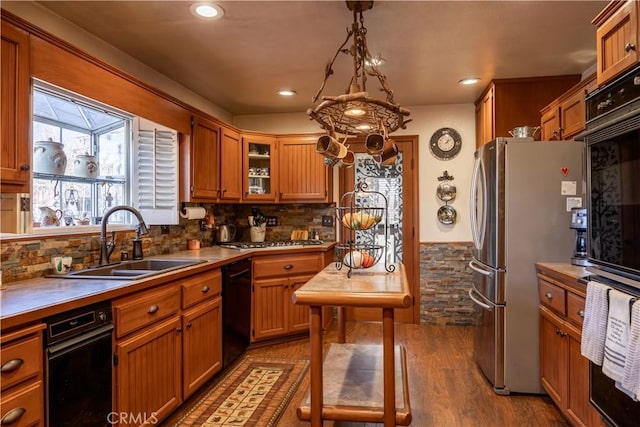 kitchen with sink, decorative light fixtures, black appliances, light hardwood / wood-style flooring, and backsplash