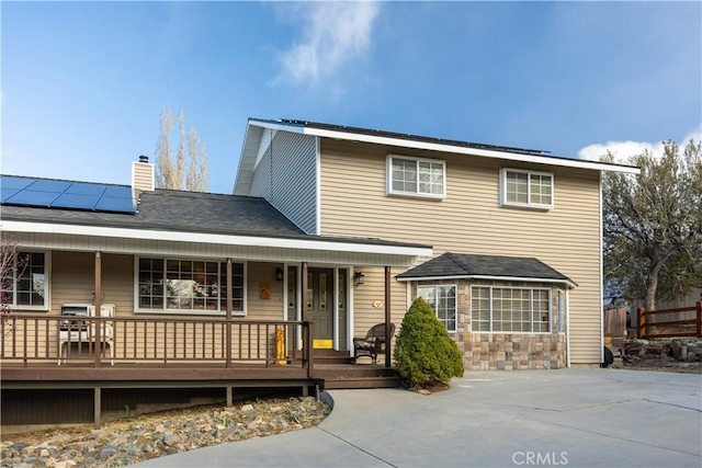 rear view of property with a porch and solar panels