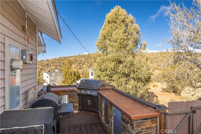 wooden terrace with an outdoor kitchen and area for grilling