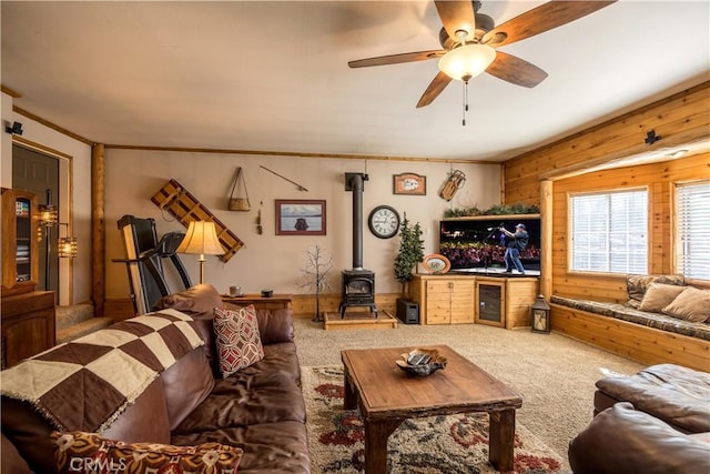 living room with wood walls, carpet flooring, a wood stove, wine cooler, and ceiling fan