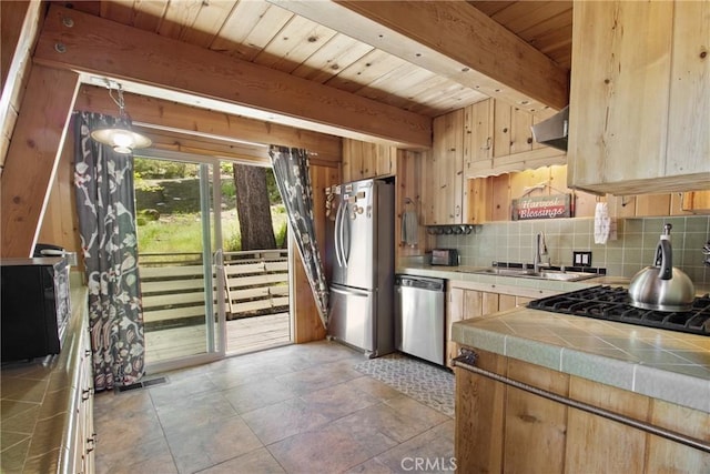 kitchen with beam ceiling, tile counters, sink, wooden ceiling, and stainless steel appliances