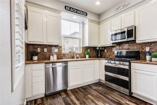 kitchen with white cabinets, dark hardwood / wood-style flooring, stainless steel appliances, and dark stone countertops