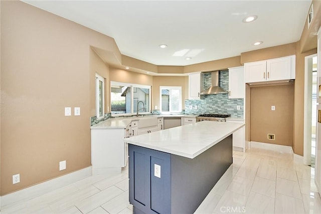 kitchen featuring white cabinets, a center island, wall chimney exhaust hood, tasteful backsplash, and stove