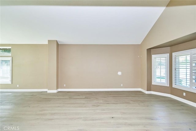 unfurnished room featuring light wood-type flooring and vaulted ceiling