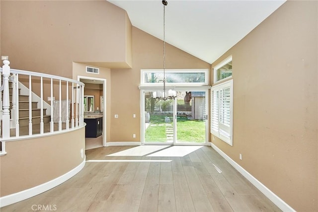 doorway featuring high vaulted ceiling, a healthy amount of sunlight, a notable chandelier, and hardwood / wood-style floors