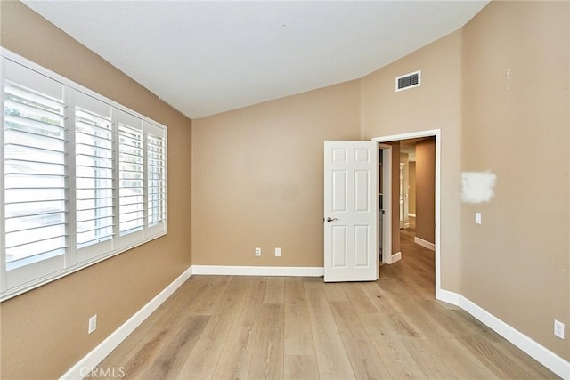 spare room featuring light hardwood / wood-style floors and lofted ceiling