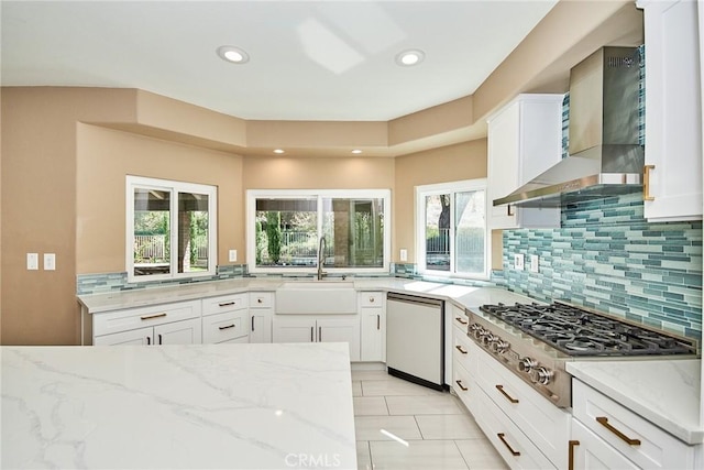 kitchen with dishwashing machine, white cabinets, and wall chimney exhaust hood