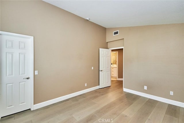 unfurnished room featuring light wood-type flooring and vaulted ceiling