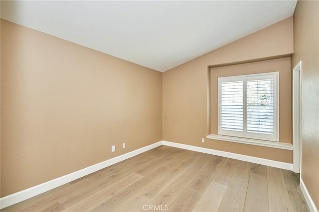 spare room with vaulted ceiling and light hardwood / wood-style floors