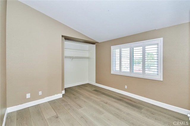 unfurnished bedroom with lofted ceiling, a closet, and light hardwood / wood-style floors