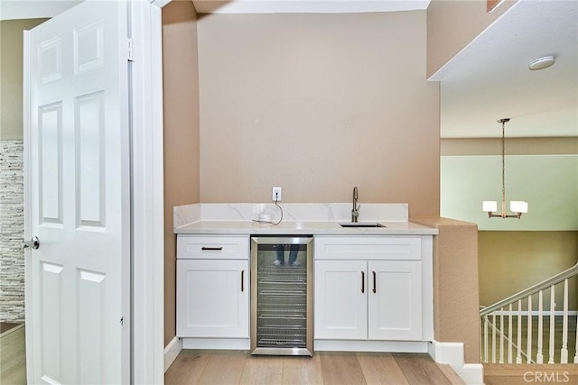 bar featuring pendant lighting, white cabinetry, wine cooler, light hardwood / wood-style floors, and sink