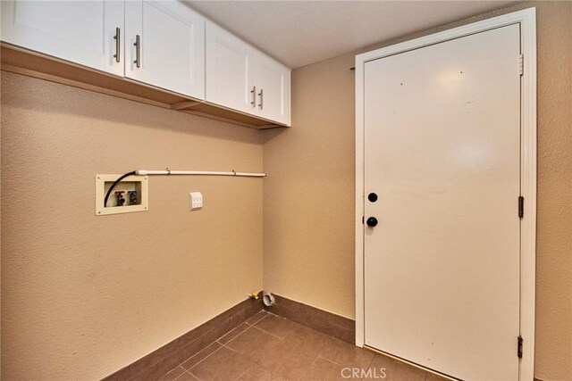 washroom featuring cabinets, dark tile patterned floors, and hookup for a washing machine